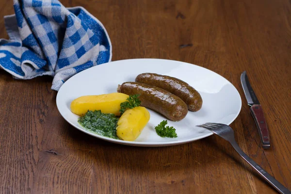 patates ve ıspanak ahşap bir masa üzerinde beyaz bir tabakta ile pişmiş sosis