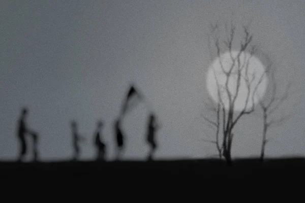 silhouette of a tree with moon and people