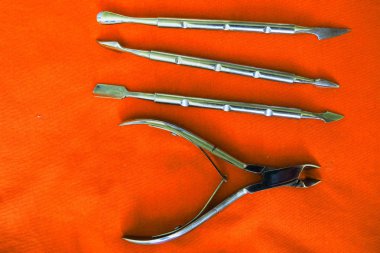 Turuncu arka plan üzerinde manikür araçları temel seti. Tırnak ve tırnak makası, mığla düzeltici, tırnak dosyası