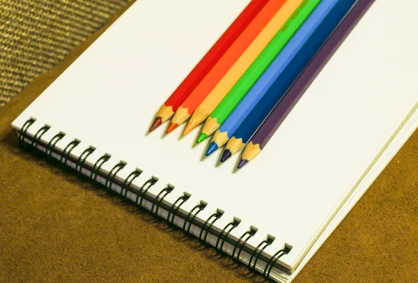 Carnet vide et crayons colorés sur fond marron — Photo