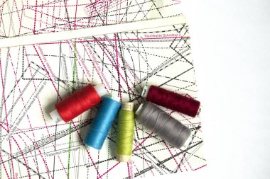 Beyaz ahşap bir masa üzerinde dikiş malzemeleri: dikiş iplik, makas, iplik büyük bir makara, bez parçaları, iğneler, santimetre,