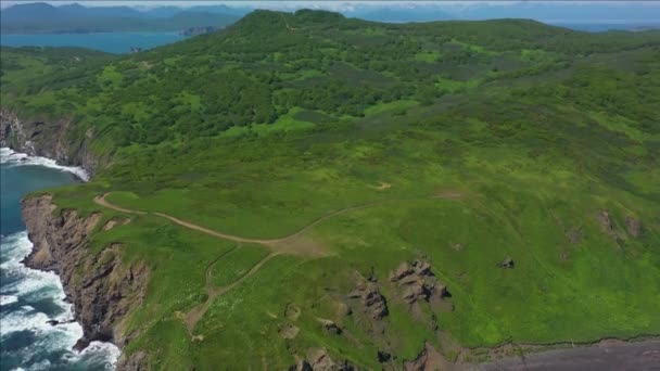 Górny widok fal rozbija się na skałach w błękitnym oceanie. Fale morskie na pięknej plaży widok z lotu drona 4k strzał. Widok ptaki fale oceanu uderzające o pustą skałę klifu z góry — Wideo stockowe