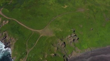 Okyanus mavi dalgalarının insansız hava aracının 4K görüntüsü kayalık bir dağın yüksek uçurumunda kırılıyor. Sahilde tehlikeli deniz dalgaları.