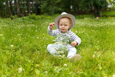 Yazlık parkın bir glade üzerinde çimoturan kamuflaj bir buket ile bir yetişkin şapka toddler