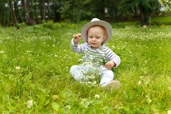 Yazlık parkın bir glade üzerinde çimoturan kamuflaj bir buket ile bir yetişkin şapka toddler