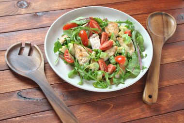 Avokado ve kiraz domates, roka ve pancar tavuk salatası bırakır. Ahşap arka plan üzerinde tavuk ve sebze ile sağlıklı öğle yemeği kase. Sağlıklı gıda kavramı