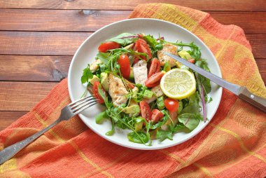 Avokado ve kiraz domates, roka ve pancar tavuk salatası bırakır. Ahşap arka plan üzerinde tavuk ve sebze ile sağlıklı öğle yemeği kase. Sağlıklı gıda kavramı