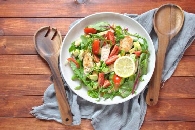 Avokado ve kiraz domates, roka ve pancar tavuk salatası bırakır. Ahşap arka plan üzerinde tavuk ve sebze ile sağlıklı öğle yemeği kase. Sağlıklı gıda kavramı