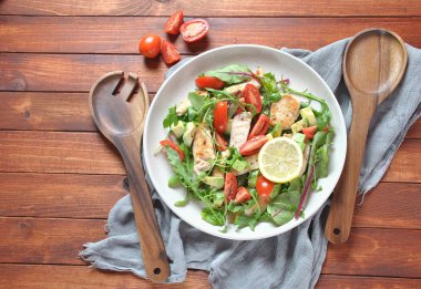 Avokado ve kiraz domates, roka ve pancar tavuk salatası bırakır. Ahşap arka plan üzerinde tavuk ve sebze ile sağlıklı öğle yemeği kase. Sağlıklı gıda kavramı