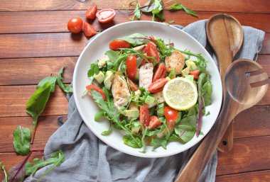 Avokado ve kiraz domates, roka ve pancar tavuk salatası bırakır. Ahşap arka plan üzerinde tavuk ve sebze ile sağlıklı öğle yemeği kase. Sağlıklı gıda kavramı