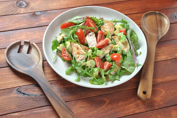 Avokado ve kiraz domates, roka ve pancar tavuk salatası bırakır. Ahşap arka plan üzerinde tavuk ve sebze ile sağlıklı öğle yemeği kase. Sağlıklı gıda kavramı