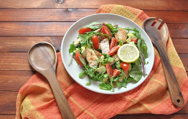 Avokado ve kiraz domates, roka ve pancar tavuk salatası bırakır. Ahşap arka plan üzerinde tavuk ve sebze ile sağlıklı öğle yemeği kase. Sağlıklı gıda kavramı