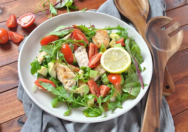 Avokado ve kiraz domates, roka ve pancar tavuk salatası bırakır. Ahşap arka plan üzerinde tavuk ve sebze ile sağlıklı öğle yemeği kase. Sağlıklı gıda kavramı