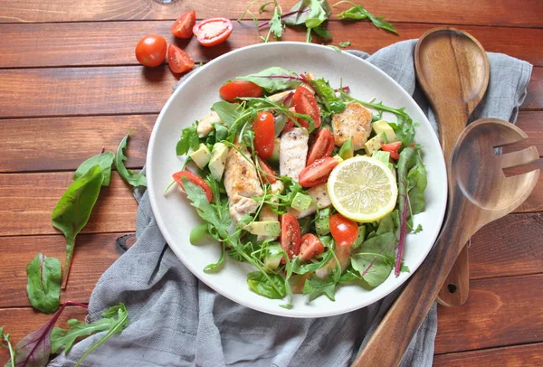 Avokado ve kiraz domates, roka ve pancar tavuk salatası bırakır. Ahşap arka plan üzerinde tavuk ve sebze ile sağlıklı öğle yemeği kase. Sağlıklı gıda kavramı