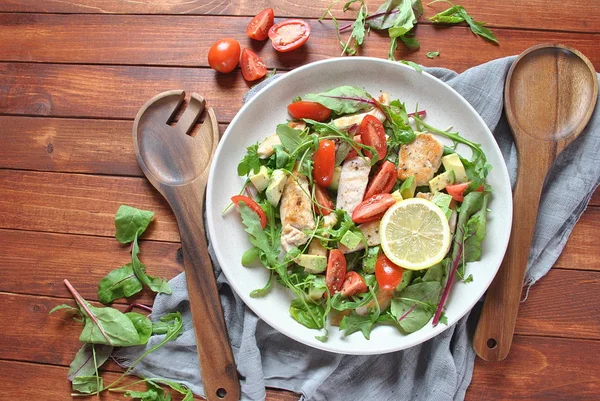 Avokado ve kiraz domates, roka ve pancar tavuk salatası bırakır. Ahşap arka plan üzerinde tavuk ve sebze ile sağlıklı öğle yemeği kase. Sağlıklı gıda kavramı