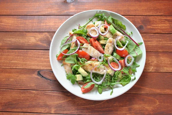 Avokado ve kiraz domates, roka ve pancar tavuk salatası bırakır. Ahşap arka plan üzerinde tavuk ve sebze ile sağlıklı öğle yemeği kase. Sağlıklı gıda kavramı
