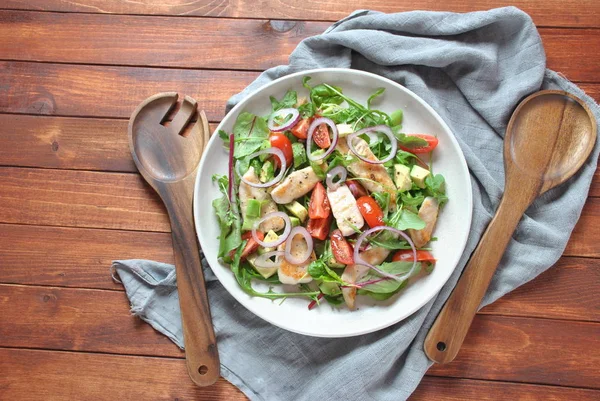 Avokado ve kiraz domates, roka ve pancar tavuk salatası bırakır. Ahşap arka plan üzerinde tavuk ve sebze ile sağlıklı öğle yemeği kase. Sağlıklı gıda kavramı