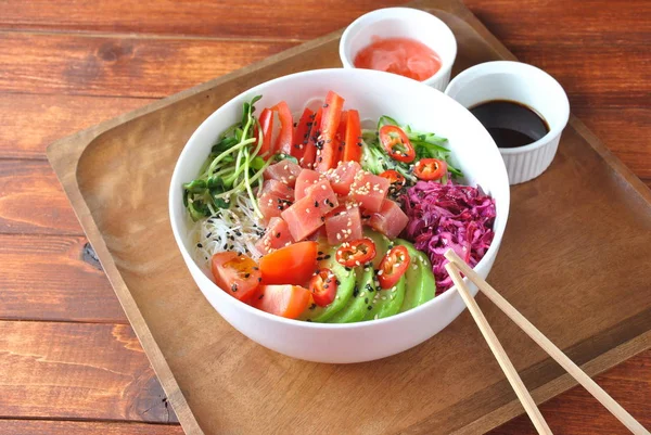 Organic food. Fresh seafood recipe. Tuna poke bowl with crystal noodles, fresh red cabbage, avocado, cherry tomatoes. Food concept poke bowl on wooden background