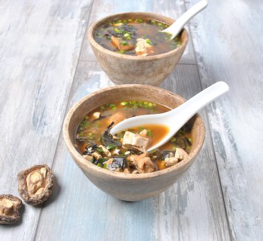 Japon miso çorbası ile taze orkinos, kurutulmuş yosun, tofu, shiitake mantar ahşap arka plan üzerinde ahşap bir kasede kurutulmuş