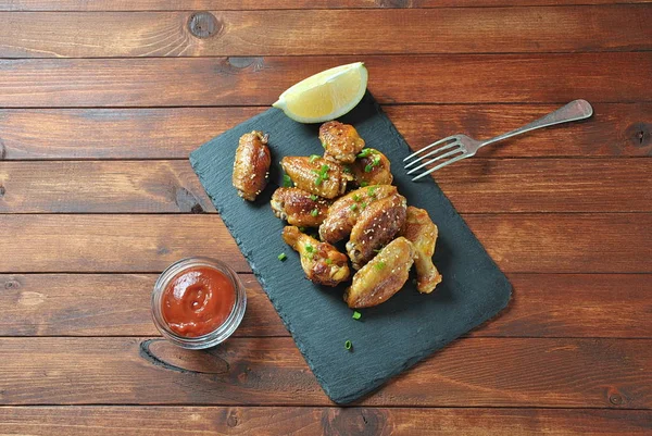 Izgara, Barbekü tavuk kanatları, akşam yemeği veya öğle yemeği için lezzetli yemekler. Susam ile kızarmış tavuk kanatları. Ahşap arka plan üzerinde fast food kavramı 