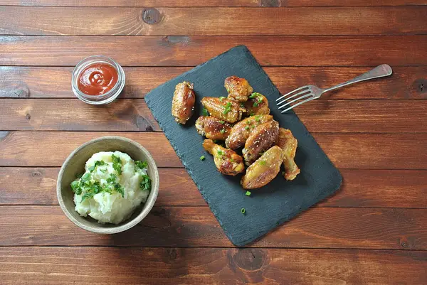 Izgara, Barbekü tavuk kanatları, akşam yemeği veya öğle yemeği için lezzetli yemekler. Susam ile kızarmış tavuk kanatları. Ahşap arka plan üzerinde fast food kavramı 