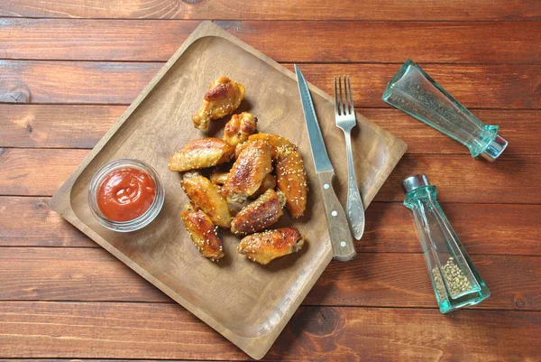 Izgara, Barbekü tavuk kanatları, akşam yemeği veya öğle yemeği için lezzetli yemekler. Susam ile kızarmış tavuk kanatları. Ahşap arka plan üzerinde fast food kavramı 