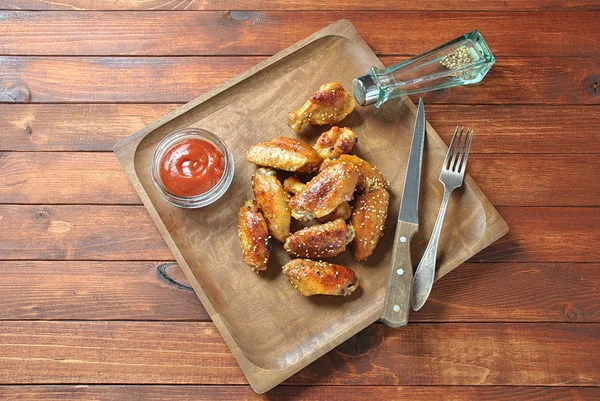 Izgara, Barbekü tavuk kanatları, akşam yemeği veya öğle yemeği için lezzetli yemekler. Susam ile kızarmış tavuk kanatları. Ahşap arka plan üzerinde fast food kavramı 