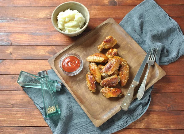 Izgara, Barbekü tavuk kanatları, akşam yemeği veya öğle yemeği için lezzetli yemekler. Susam ile kızarmış tavuk kanatları. Ahşap arka plan üzerinde fast food kavramı 