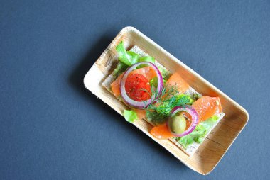 Avokado ile sağlıklı bütün tahıl crispbread yapıştırın, somon, zeytin, soğan, domates. Sağlıklı beslenme çanak