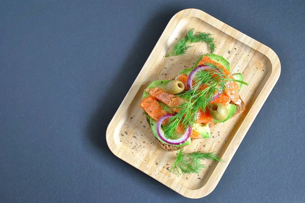 Avokado ile sağlıklı bütün tahıl crispbread yapıştırın, somon, zeytin, soğan, domates. Sağlıklı beslenme çanak