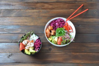 Organik gıda. Taze deniz ürünleri yemek tarifi. İki taze somon, karides, pirinç, kırmızı lahana, avokado, domates ile kase poke ve ahşap arka plan üzerinde turp lahanası. Gıda kavramı Poke kase 