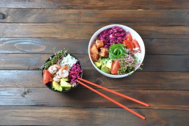 Organik gıda. Taze deniz ürünleri yemek tarifi. İki taze somon, karides, pirinç, kırmızı lahana, avokado, domates ile kase poke ve ahşap arka plan üzerinde turp lahanası. Gıda kavramı Poke kase 