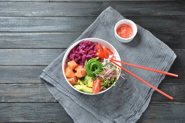 Organik gıda. Taze deniz ürünleri yemek tarifi. Taze somon poke kase pirinç, taze kırmızı lahana, avokado, kiraz domates, salatalık, turp lahanası ahşap arka plan üzerinde. Gıda kavramı poke kase 