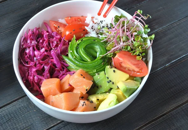 Organik gıda. Taze deniz ürünleri yemek tarifi. Taze somon poke kase pirinç, taze kırmızı lahana, avokado, kiraz domates, salatalık, turp lahanası ahşap arka plan üzerinde. Gıda kavramı poke kase 