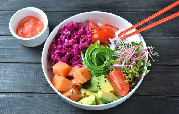 Organik gıda. Taze deniz ürünleri yemek tarifi. Taze somon poke kase pirinç, taze kırmızı lahana, avokado, kiraz domates, salatalık, turp lahanası ahşap arka plan üzerinde. Gıda kavramı poke kase 