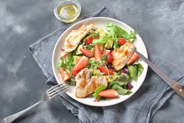 Tavuk avokado, çilek, mavi peynir, roka salatası, pancar yaprakları. Sağlıklı yemek avokado kase, tavuk ve koyu gri arka plan üzerinde çilek ile plaka. Sağlıklı gıda kavramı