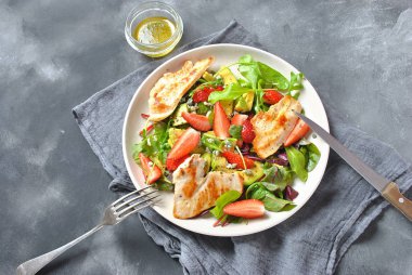 Tavuk avokado, çilek, mavi peynir, roka salatası, pancar yaprakları. Sağlıklı yemek avokado kase, tavuk ve koyu gri arka plan üzerinde çilek ile plaka. Sağlıklı gıda kavramı