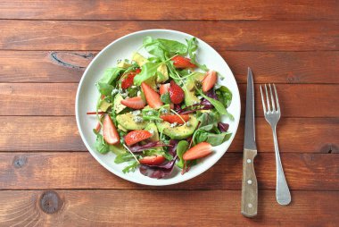 Avokado salatası çilek, mavi peynir, roka ve pancar ahşap arka plan üzerinde bırakır. Sağlıklı öğle yemeği kase Vegan sağlıklı gıda kavramı 