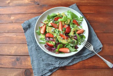 Avokado salatası çilek, mavi peynir, roka ve pancar ahşap arka plan üzerinde bırakır. Sağlıklı öğle yemeği kase Vegan sağlıklı gıda kavramı 