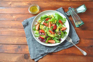 Avokado salatası çilek, mavi peynir, roka ve pancar ahşap arka plan üzerinde bırakır. Sağlıklı öğle yemeği kase Vegan sağlıklı gıda kavramı 