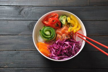 Kase taze somon, kristal erişte, turp, avokado, tatlı biber, salatalık, susam, kırmızı lahana ile poke. Organik gıda. Taze deniz ürünleri yemek tarifi. Gıda kavramı poke kase ahşap arka plan üzerinde 