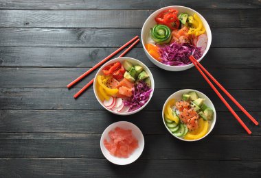 Kase taze somon, kristal erişte, turp, avokado, tatlı biber, salatalık, susam, kırmızı lahana ile poke. Organik gıda. Taze deniz ürünleri yemek tarifi. Gıda kavramı poke kase ahşap arka plan üzerinde 