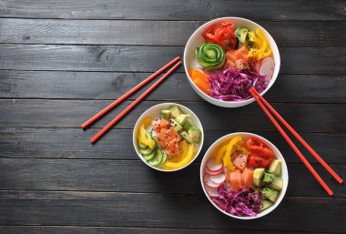 Kase taze somon, kristal erişte, turp, avokado, tatlı biber, salatalık, susam, kırmızı lahana ile poke. Organik gıda. Taze deniz ürünleri yemek tarifi. Gıda kavramı poke kase ahşap arka plan üzerinde 