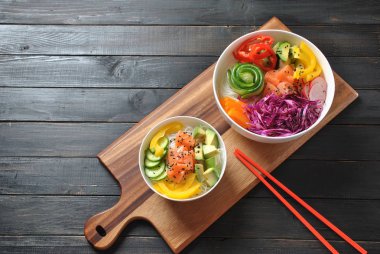 Kase taze somon, kristal erişte, turp, avokado, tatlı biber, salatalık, susam, kırmızı lahana ile poke. Organik gıda. Taze deniz ürünleri yemek tarifi. Gıda kavramı poke kase ahşap arka plan üzerinde 