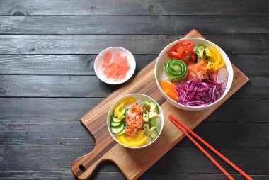 Kase taze somon, kristal erişte, turp, avokado, tatlı biber, salatalık, susam, kırmızı lahana ile poke. Organik gıda. Taze deniz ürünleri yemek tarifi. Gıda kavramı poke kase ahşap arka plan üzerinde 