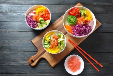 Kase taze somon, kristal erişte, turp, avokado, tatlı biber, salatalık, susam, kırmızı lahana ile poke. Organik gıda. Taze deniz ürünleri yemek tarifi. Gıda kavramı poke kase ahşap arka plan üzerinde 