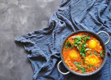 Rustik gri bir arka plan üzerinde tavada Shakshuka. Orta Doğu geleneksel yemekleri. Sebze Fried yumurta. Metin için yer. Üstten görünüm. . 