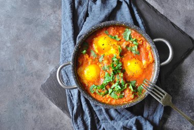 Rustik gri bir arka plan üzerinde tavada Shakshuka. Orta Doğu geleneksel yemekleri. Sebze Fried yumurta. Metin için yer. Üstten görünüm. . 