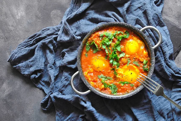 Rustik gri bir arka plan üzerinde tavada Shakshuka. Orta Doğu geleneksel yemekleri. Sebze Fried yumurta. Metin için yer. Üstten görünüm. . 