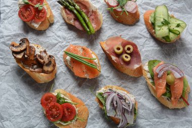 Brushetta veya geleneksel Ispanyol tapas. Italyan Antipasti aperatifler ile meze. Prosciutto ile küçük sandviç çeşitleri, kiraz domates, somon, krem peyniri, salatalık, turp, kuşkonmadan